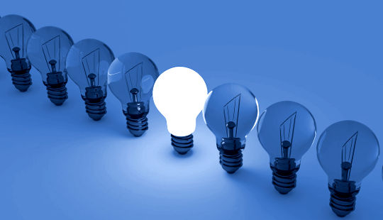 one lightbulb lit up in a row of unlit lightbulbs